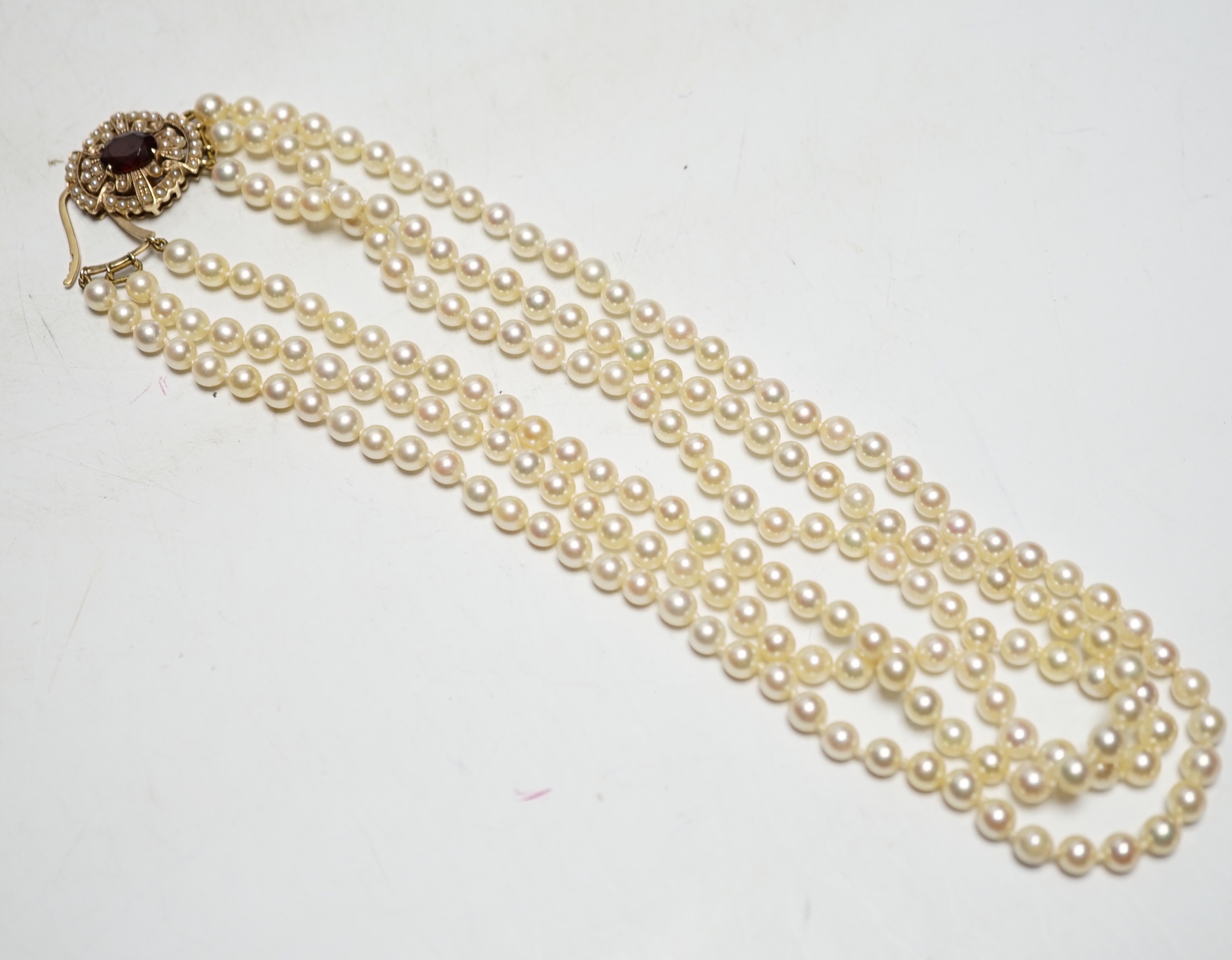 A 1960's triple strand cultured pearl necklace, by Cropp & Farr, with 9ct gold, garnet and seed pearl set clasp, 40cm.